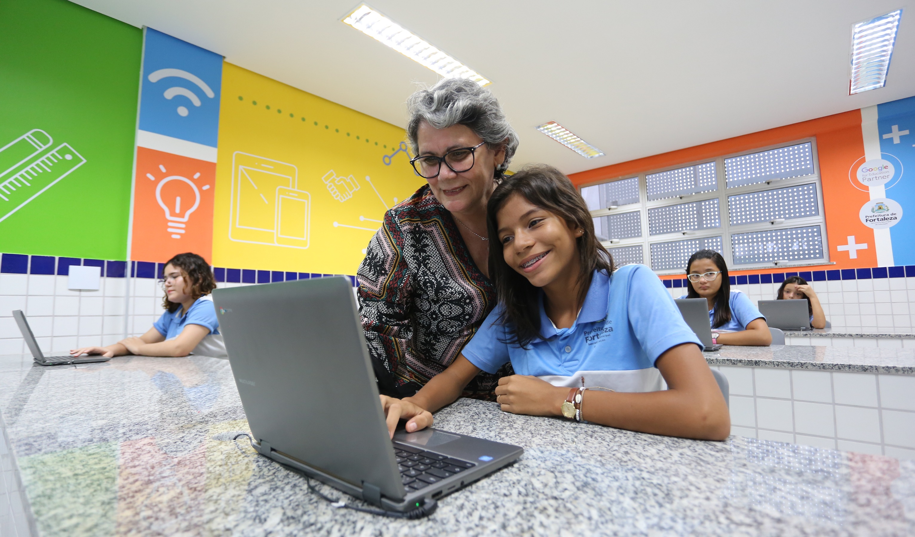 professora e aluna olham um notebook